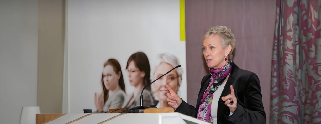 Inga Beale speaking on a stage.
