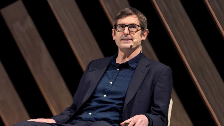Louis Theroux speaking on a stage.